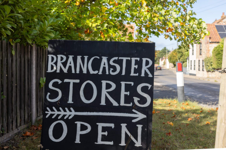 A chalkboard states 'Brancaster Stores Open'
