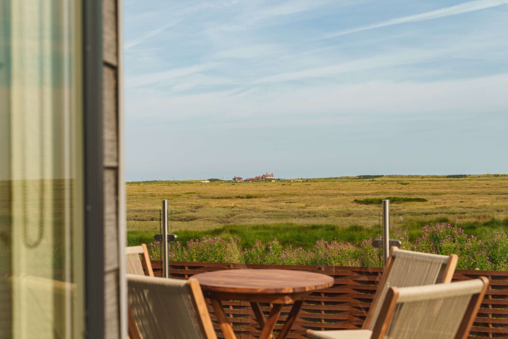 A table and chairs on static caravan decking looking out over the marshes in Brancaster