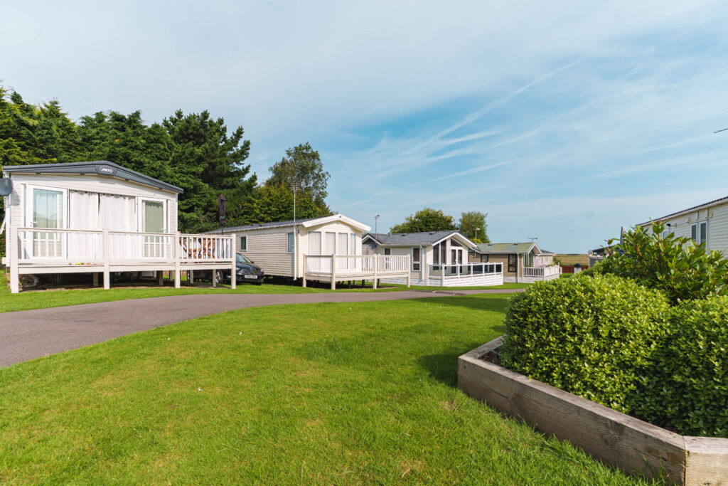 Three static caravans on grass with trees and blue sky
