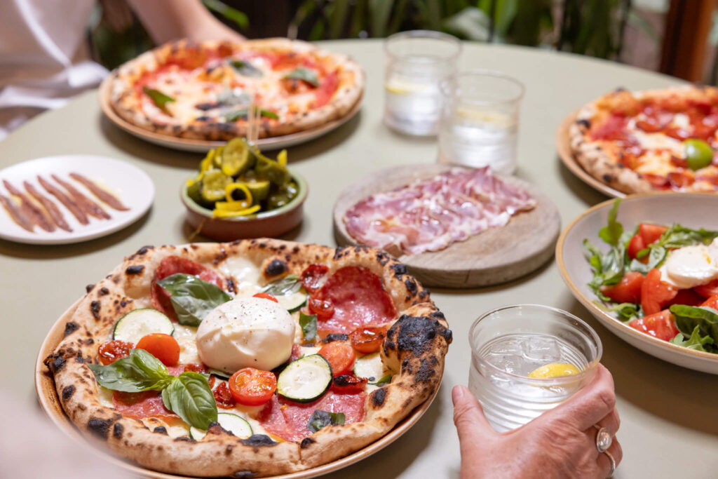 A selection of wood-fired pizza, antipasti and drinks on a table at Eric's in Drove Orchards, Thornham