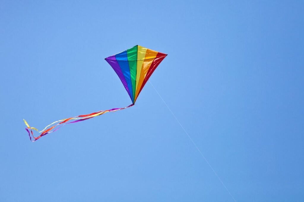 A rainbow coloured kite in a bright blue sky