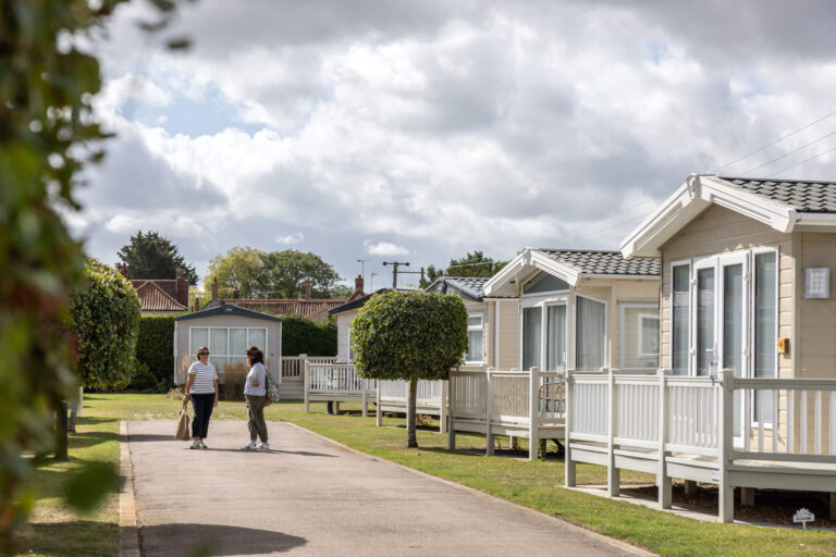 Two women chat on a path by some caravan holiday homes