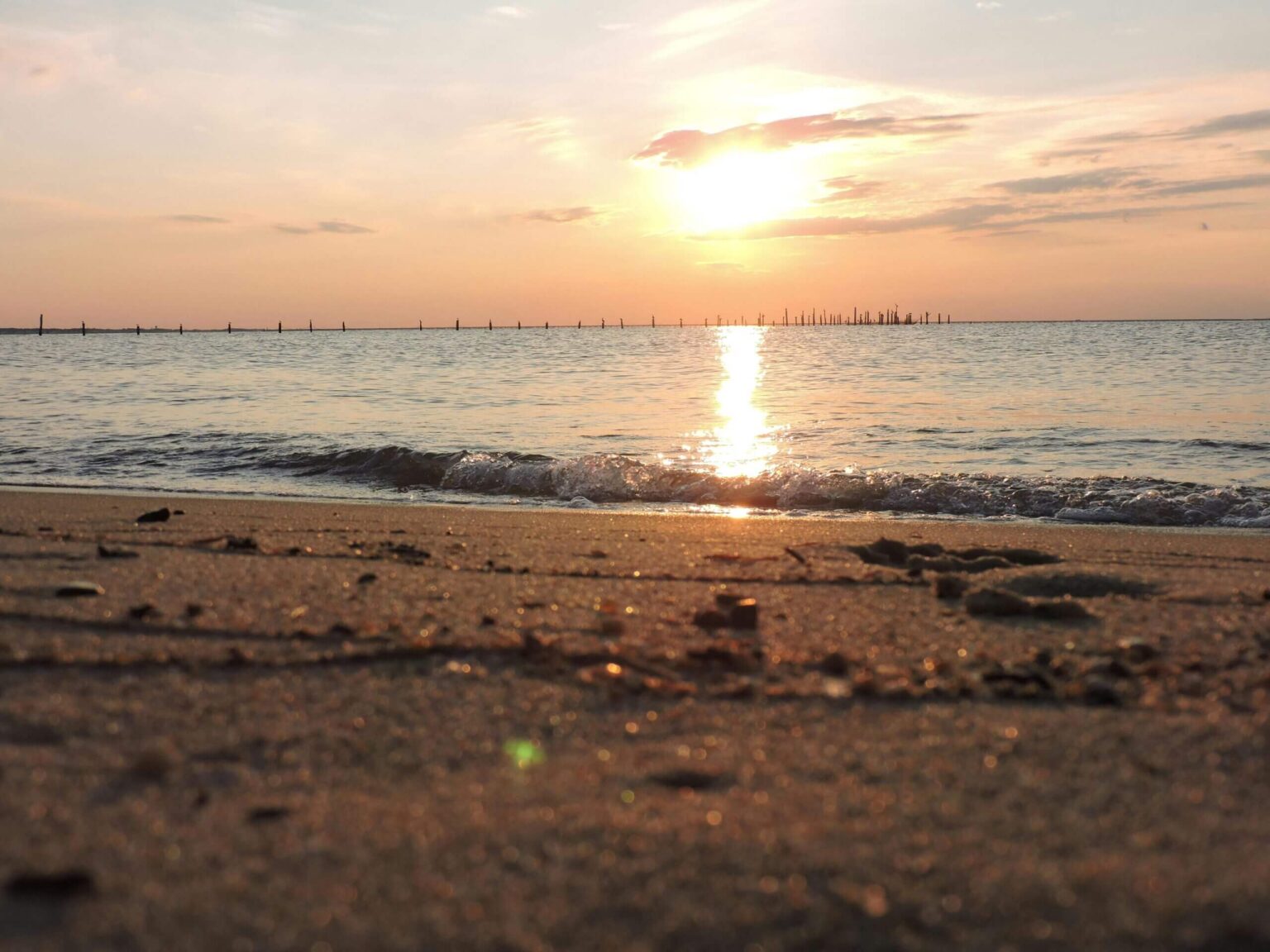 The sun sets over the sea as gentle waves lap the shore in Norfolk