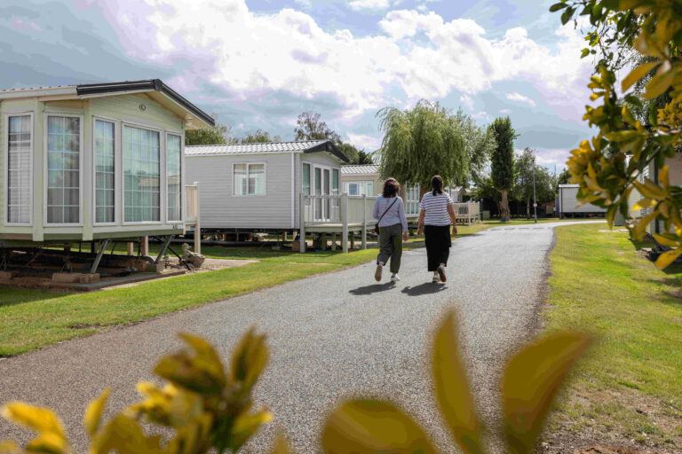 Two women walk away from the camera along a path on a caravan park